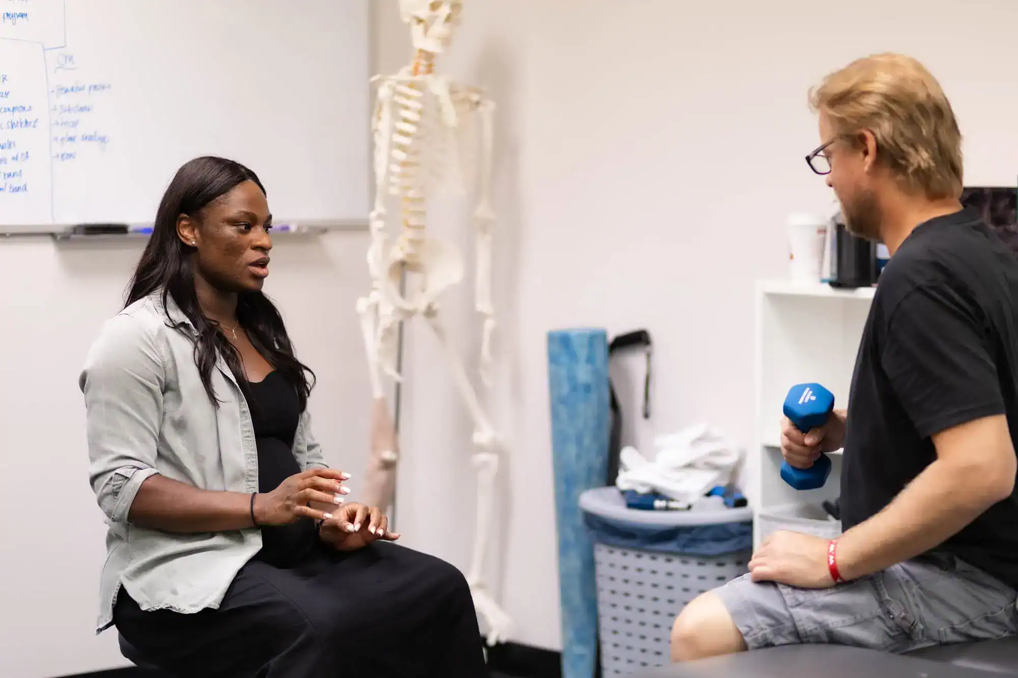 Therapist coaching a patient through strength training exercise during reconditioning session