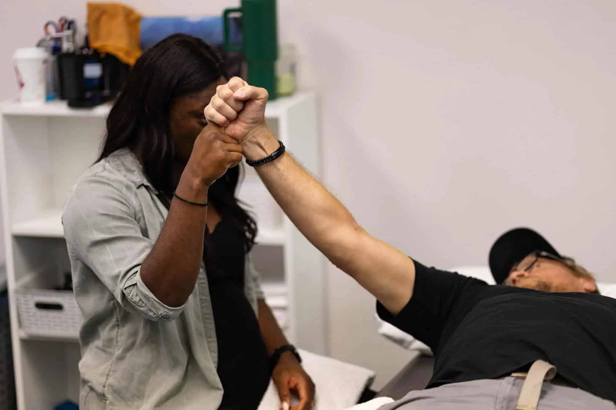 Physiotherapist assessing a patient’s arm movement during a minor injury evaluation