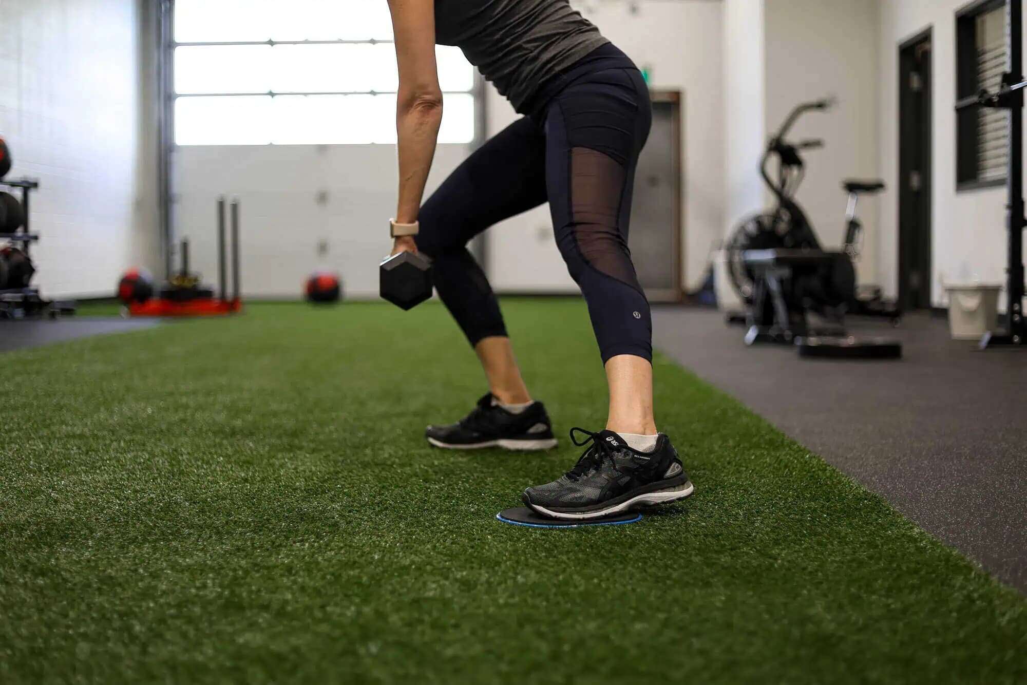 Athlete performing a weighted lunge exercise on turf during performance training session